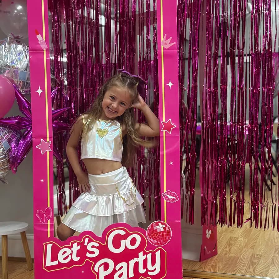 Birthday girl posing in a Barbie-themed Let's Go Party photo cutout