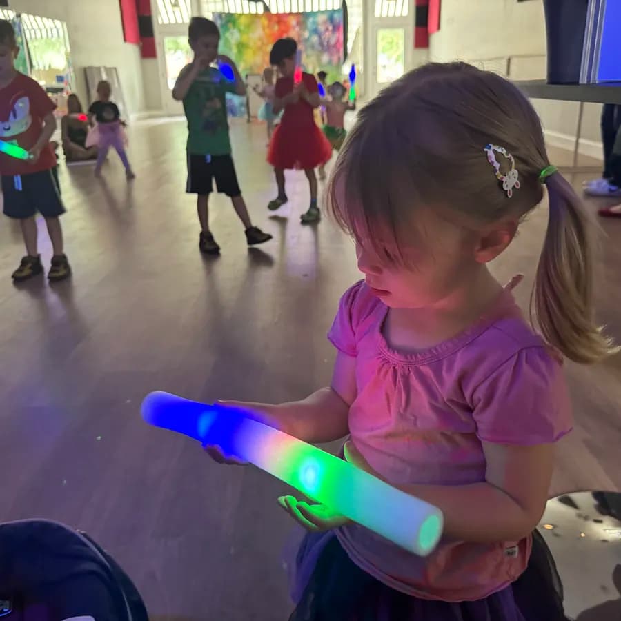 Young dancer holding glowing light wand during a glow-stick birthday dance party